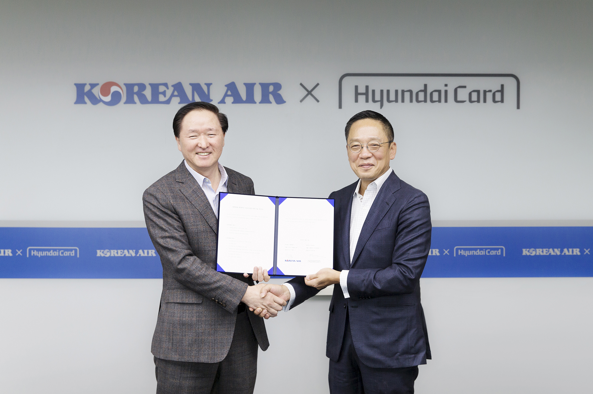 Woo Kee-hong (left), president of the Korean Air Lines, shakes hands with Hyundai Card Vice Chairman and CEO Ted Chung after singing a partnership deal for PLCC business.